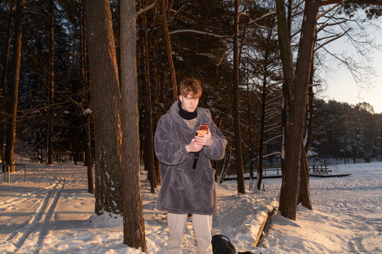 Man Using Phone On Tripod At Frozen Lake at Sunrise