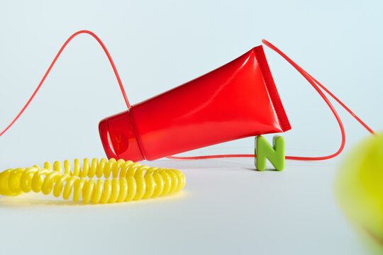 Red hand cream tube and yellow scrunchy on light blue background.