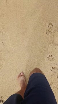 A view of feet walking on the sand of the beach, a moment of relaxation on vacation, at the beach.