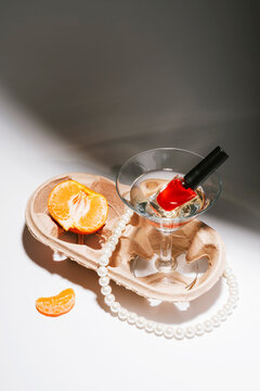 Elegant chaos of a pile of accessories, martini glass and tangerine
