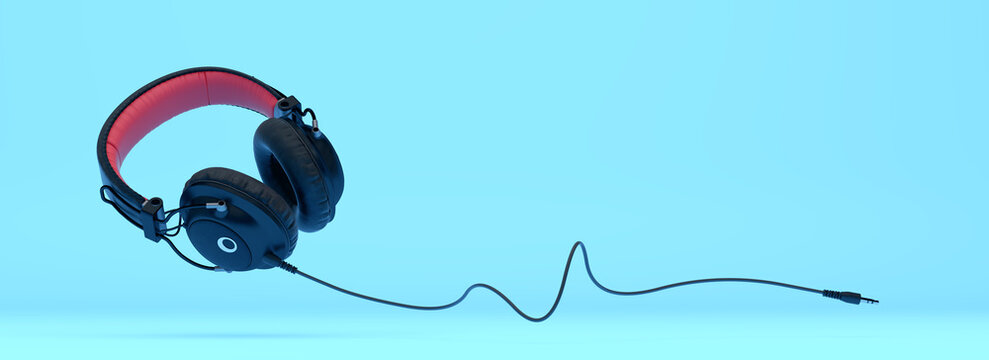 Black and red over-ear headphones with jack cable and copy space on a vibrant blue background. Modern minimalist concept for music streaming advertisement or audio podcast cover.