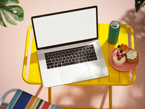 summery vibe with Laptop, cupcakes and drink on a yellow table