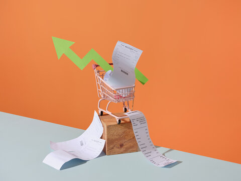 Shopping cart with receipts and a green arrow symbolizing