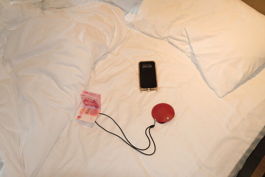 Items on a bed include a phone showing time