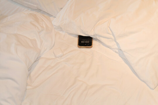 Smartphone resting on bed under pillows at night