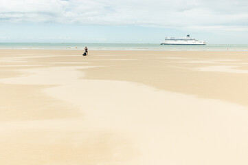 personne seule sur la plage avec un bateau au loin, vacances. Ferry sur la Manche partant pour l'Angleterre depuis la grande plage de Calais