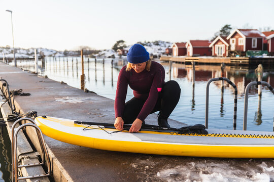 Woman Adjusting Equipment on Inflatable SUP After Winter Session