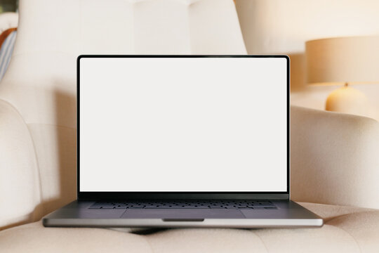 Laptop mockup with white screen on armchair indoors