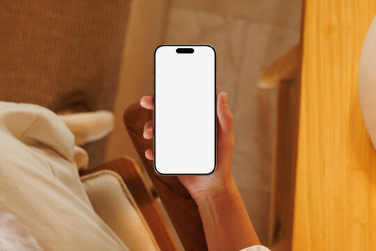 Hand holding smartphone with blank mockup screen indoors