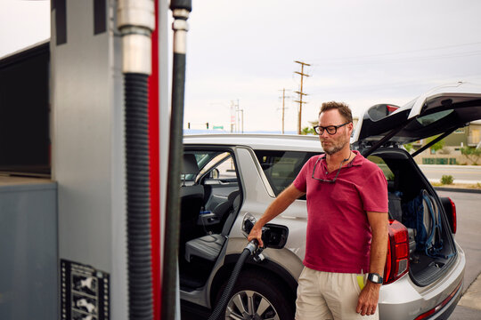 Man is filling up the vehicle at a gas station.