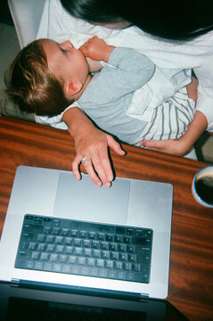 Businesswoman Holding Baby By Laptop, Film Photo