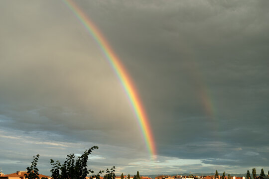 Rainbow Appears Over City After Rainstorm in Evening Sky
