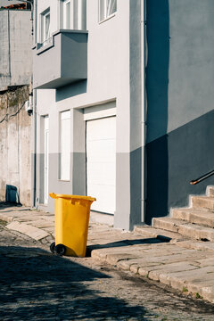 Yellow Trash Bin on Street Beside Building in Urban Area