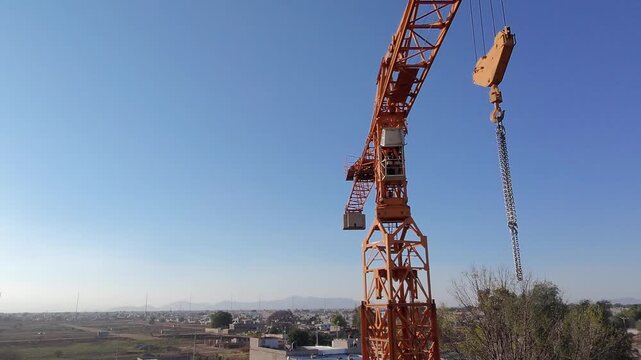 Toma cinematogr&aacute;fica realizada con drone que ejecuta un movimiento circular (&oacute;rbita) hacia la izquierda alrededor de una gr&uacute;a torre industrial.