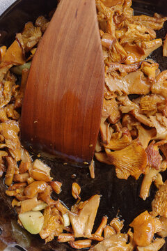 Cooking Mushrooms in a Skillet With a Wooden Spoon at Home