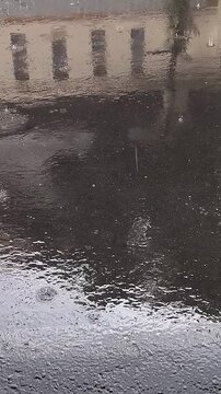 Rainy day scene with water on the ground and building reflection.