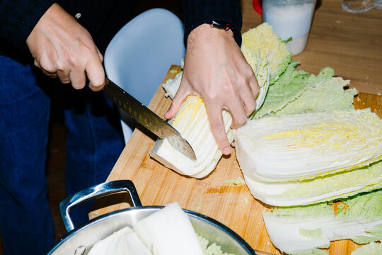 Unknown person chopping cabbage on a cutting board with kitchen knife