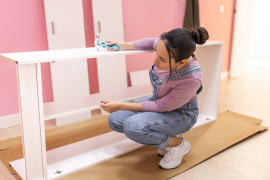 Woman tightening screws on partially assembled wardrobe