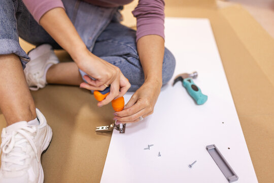 Close up of hands tightening screw on furniture