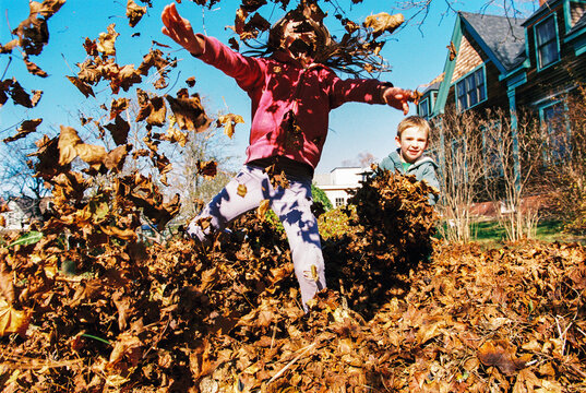 Fun Action Moment of Child Jumping in Pile of Autumn Leaves