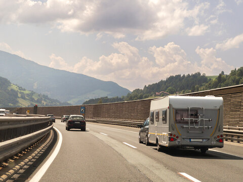 A car with a camper caravan travels on a Highway on a Sunny Day