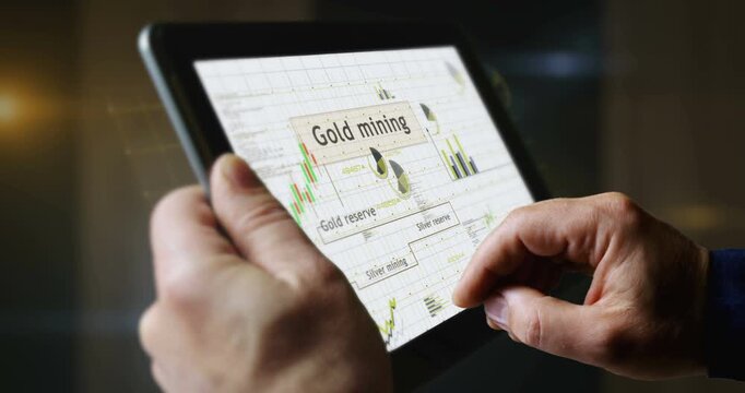 Gold and silver reserve charts and graphs diagram on touchscreen pad display. Finger touch tablet screen in hand. Digital analysis and report.