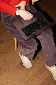 Woman using laptop while sitting on wooden chair