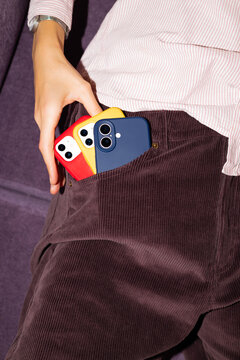 Hand placing smartphones in corduroy pants pocket