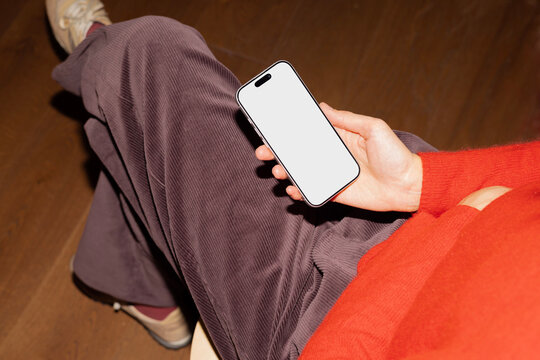 Business professional holding smartphone with blank screen indoors