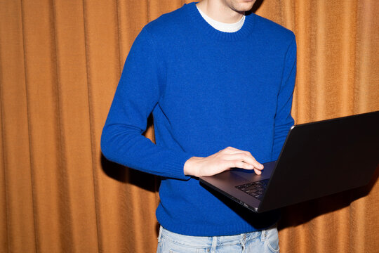 Man typing on laptop in blue sweater
