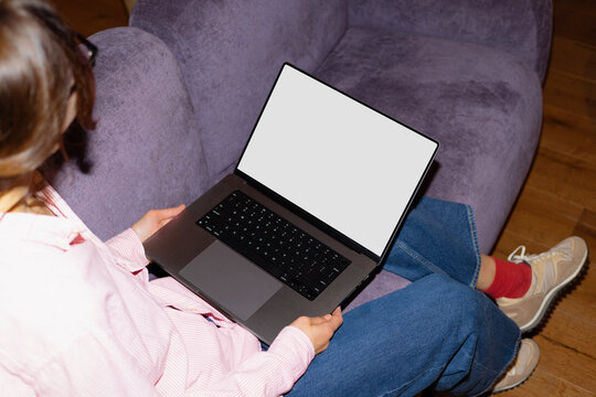 Woman holding laptop with white mockup screen indoors