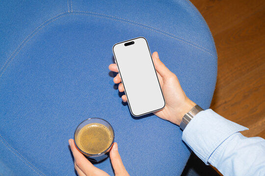 Businessperson holding smartphone and coffee indoors