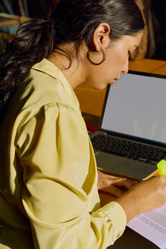 Woman Reviewing Printed Document Beside Laptop