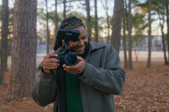 Man Holding Camera in Forest During Daylight Hours