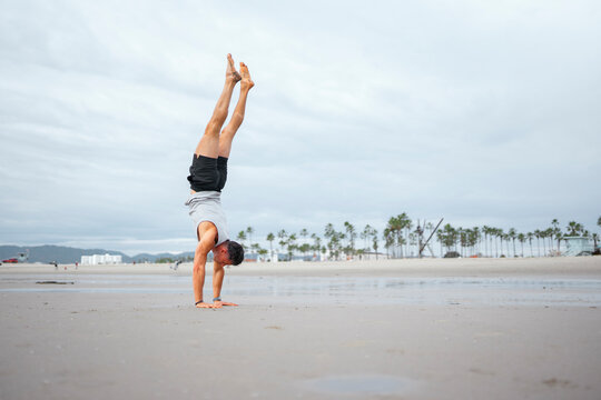 Man doing handstand on beach

