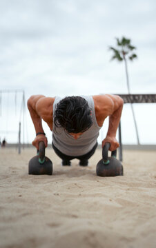 Man does push-ups on beach sand
