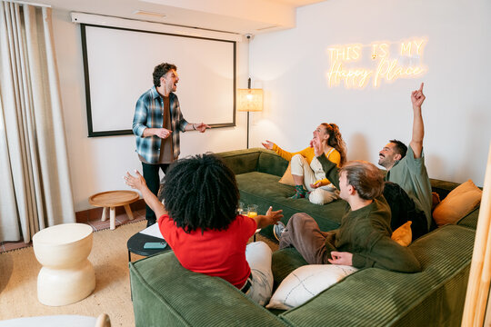 Friends playing charades game, laughing during social gathering
