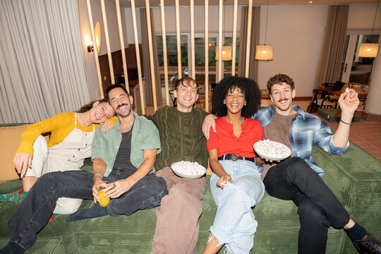 Diverse friends laughing enjoying movie night at home