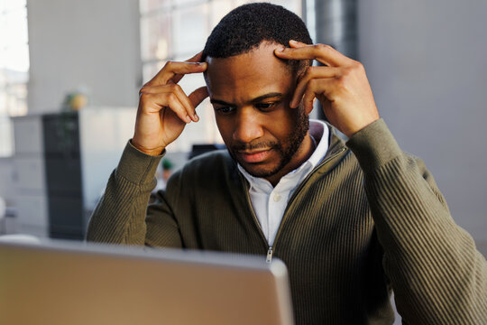 Stressed businessman struggling with headache at laptop