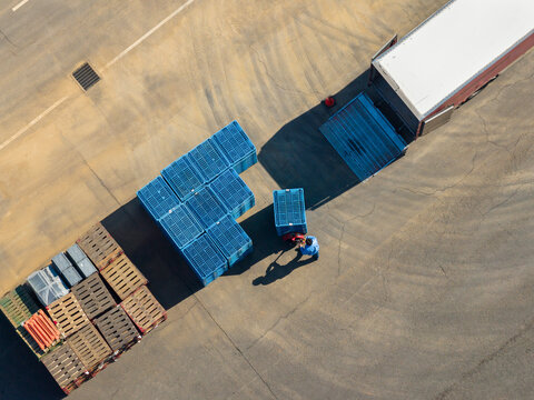 Aerial View of Worker with Blue Crates Loading Dock with Truck.
