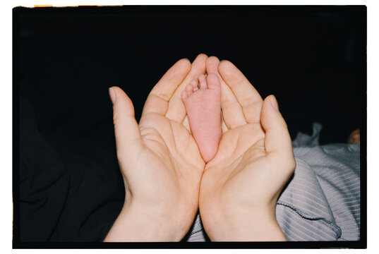 Baby foot resting in hands during evening time