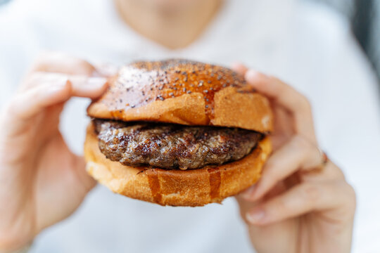 Person holding a grilled beef burger