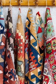 Colorful woven rugs hanging on wall hooks