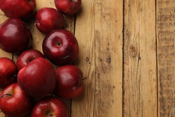 Fresh ripe red apples on wooden table, flat lay. Space for text