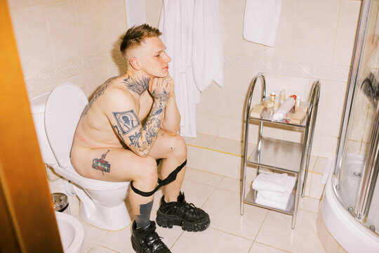 Man Sits on Toilet in Bathroom, Thinking Quietly During Morning