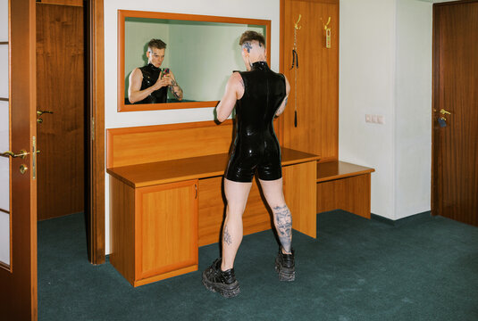 Person Stands in Front of Mirror Wearing Black Outfit in a Room