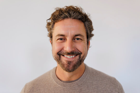 Headshot of a mature man looking at camera against neutral background