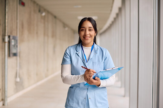 Happy nurse working at doctor's office and looking at camera.