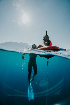 freediver surfacing next to his son sitting on a buoy in greece