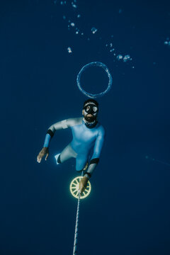 freediver making bubble ring at depth holding training line in m